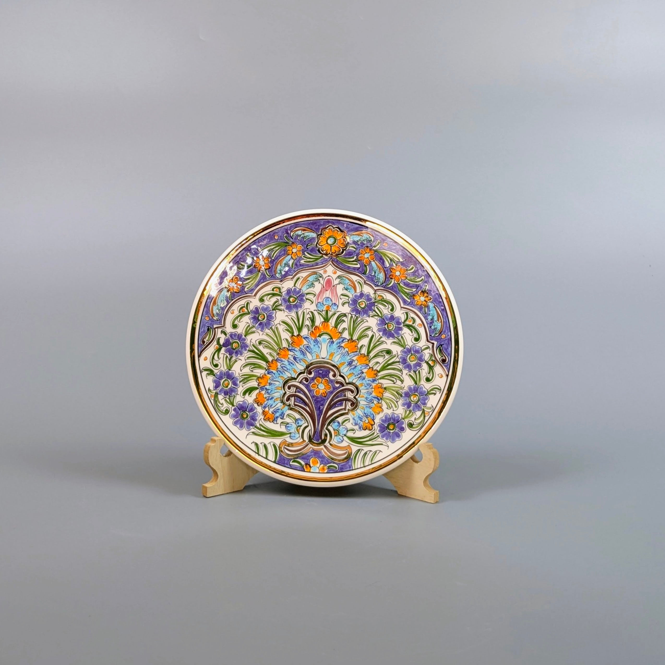 Decorative plate with floral patterns on a stand against a gray background