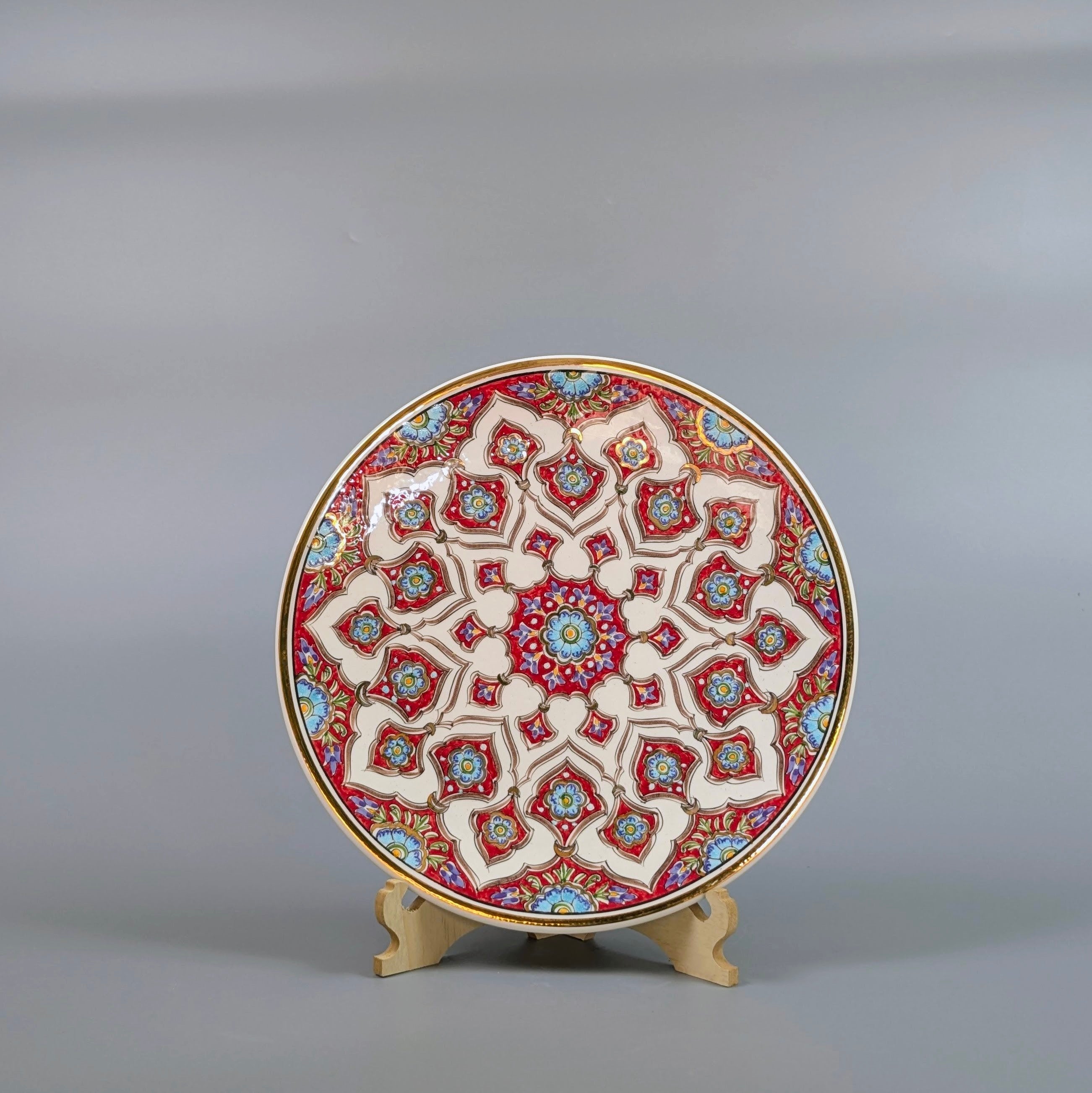 Decorative plate with intricate geometric pattern on a stand against a gray background