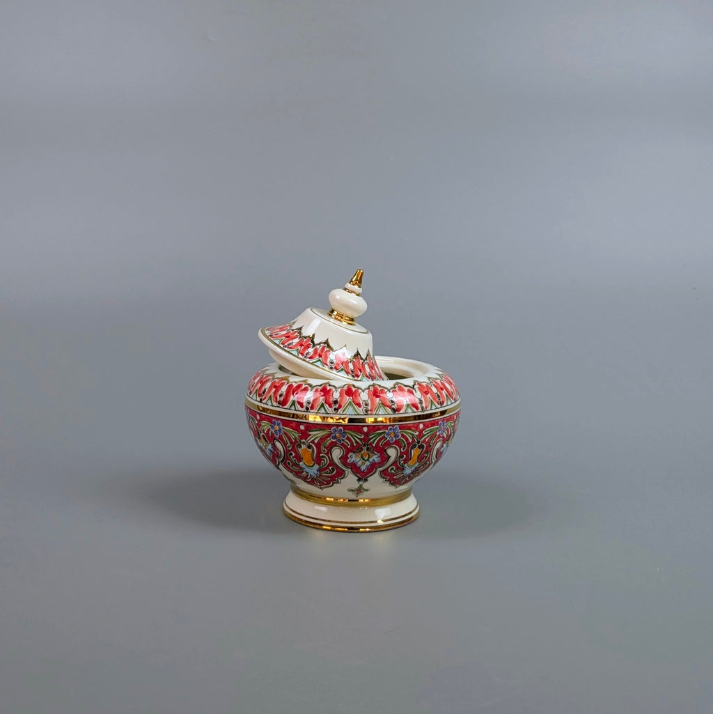 Decorative ceramic container with intricate designs on a gray background