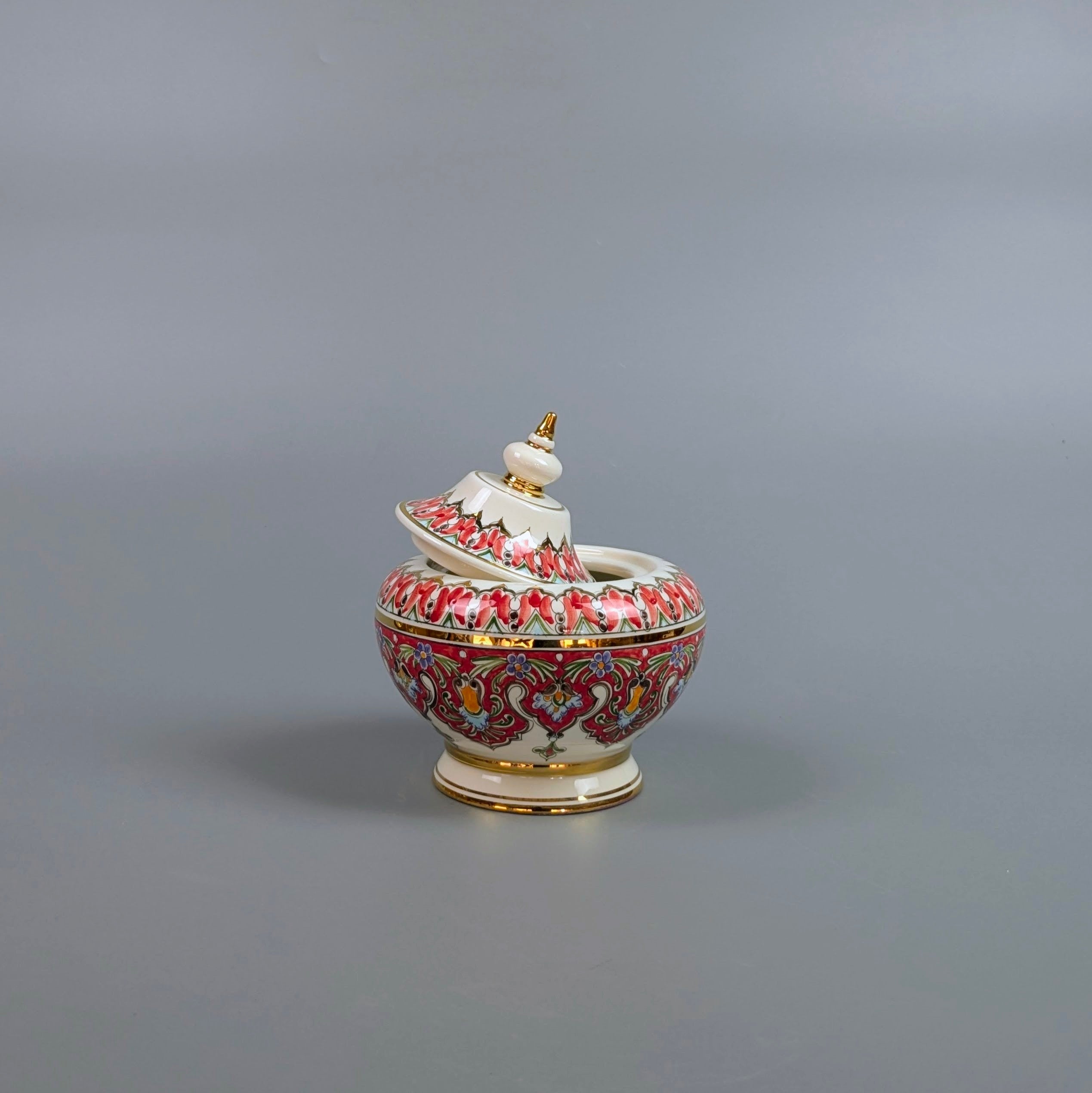Decorative ceramic container with intricate designs on a gray background