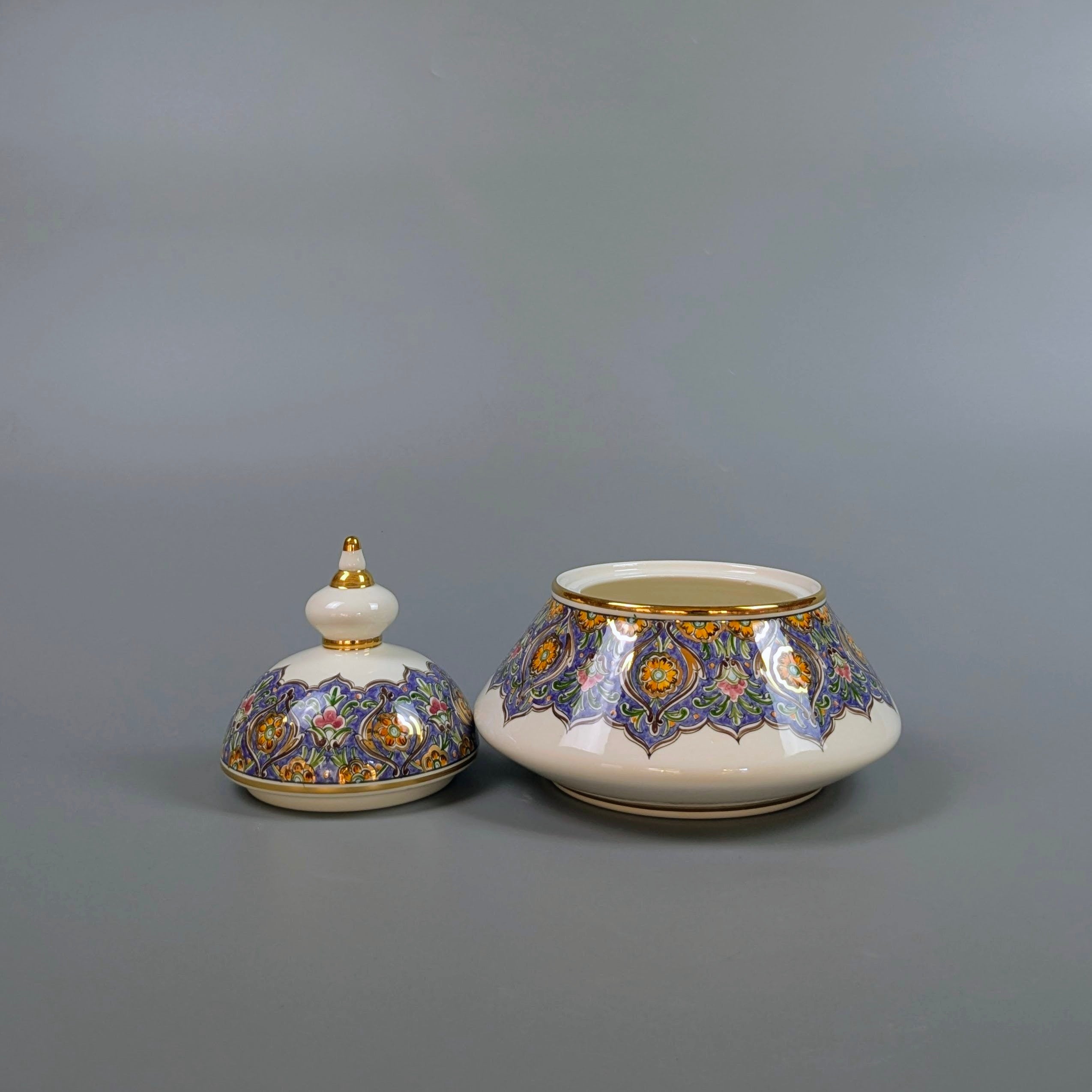 Two ceramic pots with decorative lids on a gray background