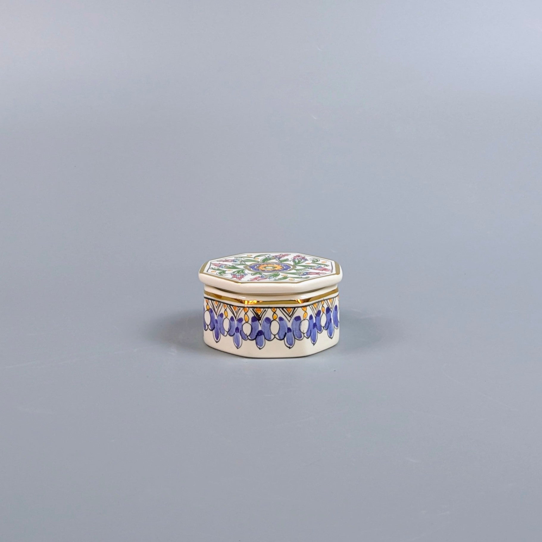 Decorative hexagonal box with floral design and blue accents on a gray background