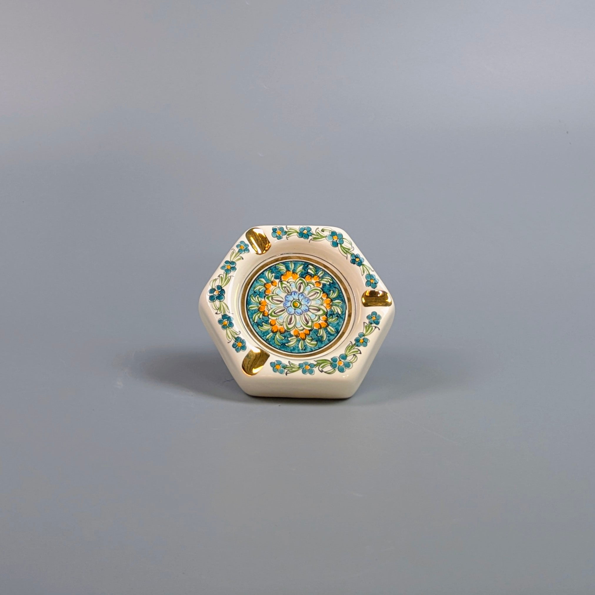 Decorative ceramic hexagonal object with floral patterns on a gray background