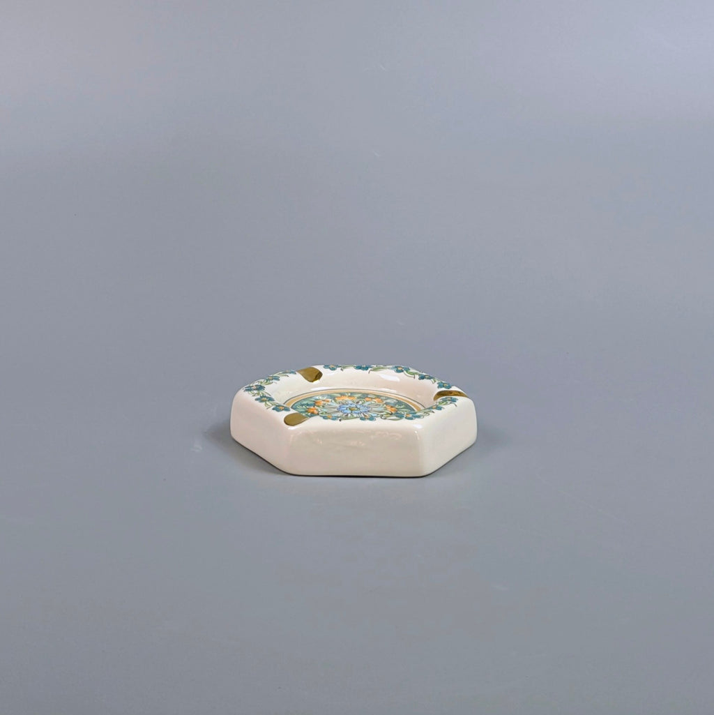 Decorative ceramic ashtray with floral patterns on a gray background