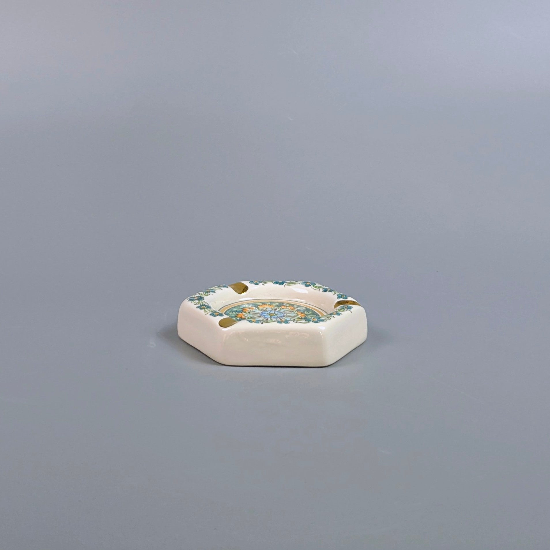 Decorative ceramic ashtray with floral patterns on a gray background