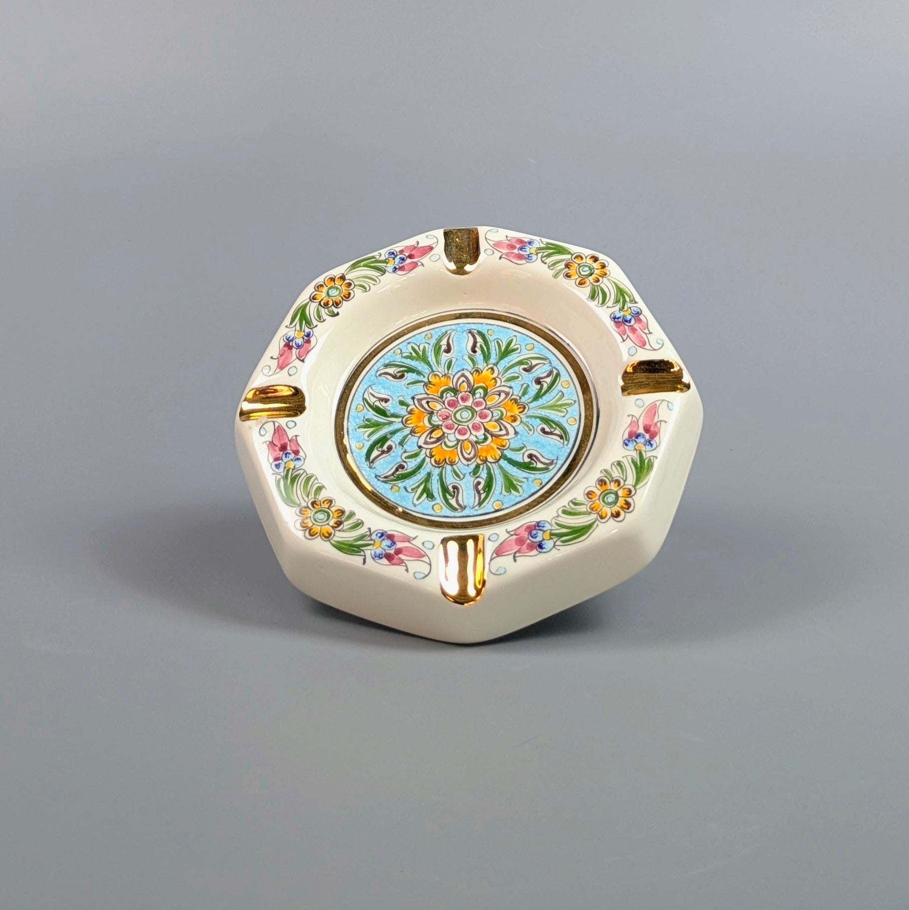 Decorative ceramic ashtray with floral patterns on a gray background