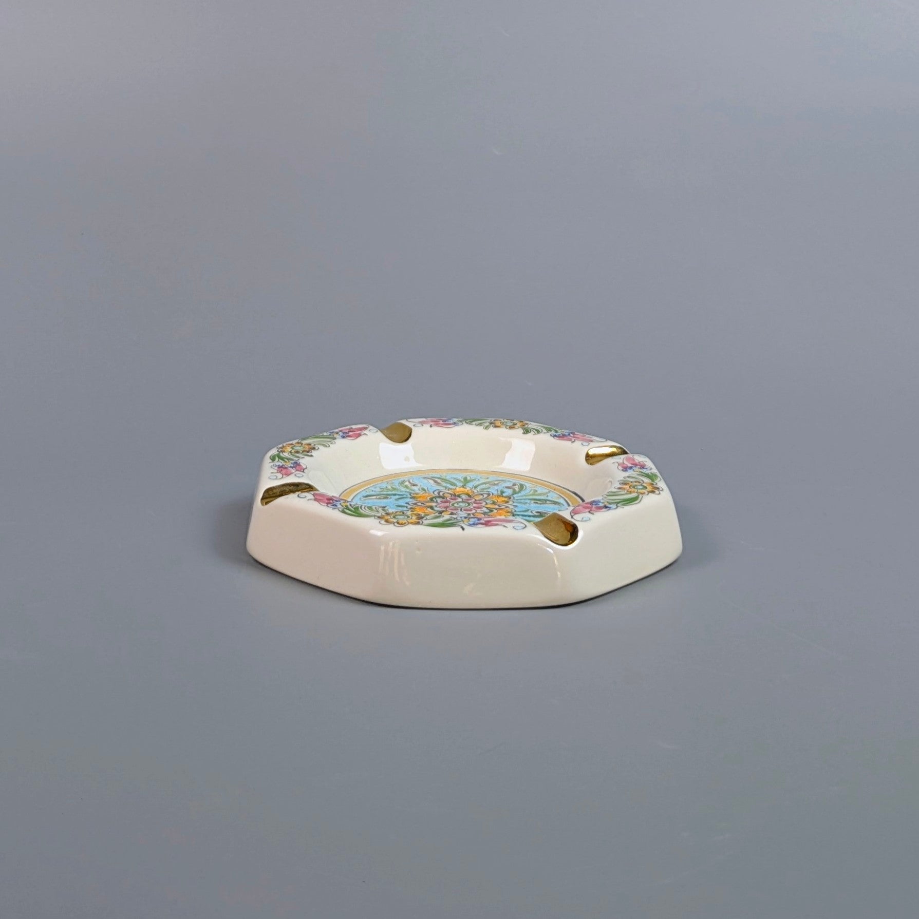 Decorative ceramic ashtray with floral design on a gray background